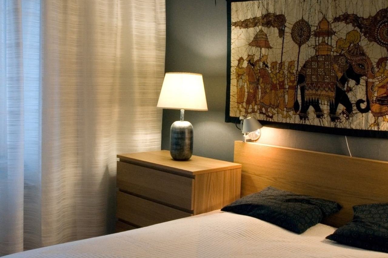 Chambre à coucher : lit avec tête de lit en bois, table de nuit, lampe de chevet et cadre accroché au mur.